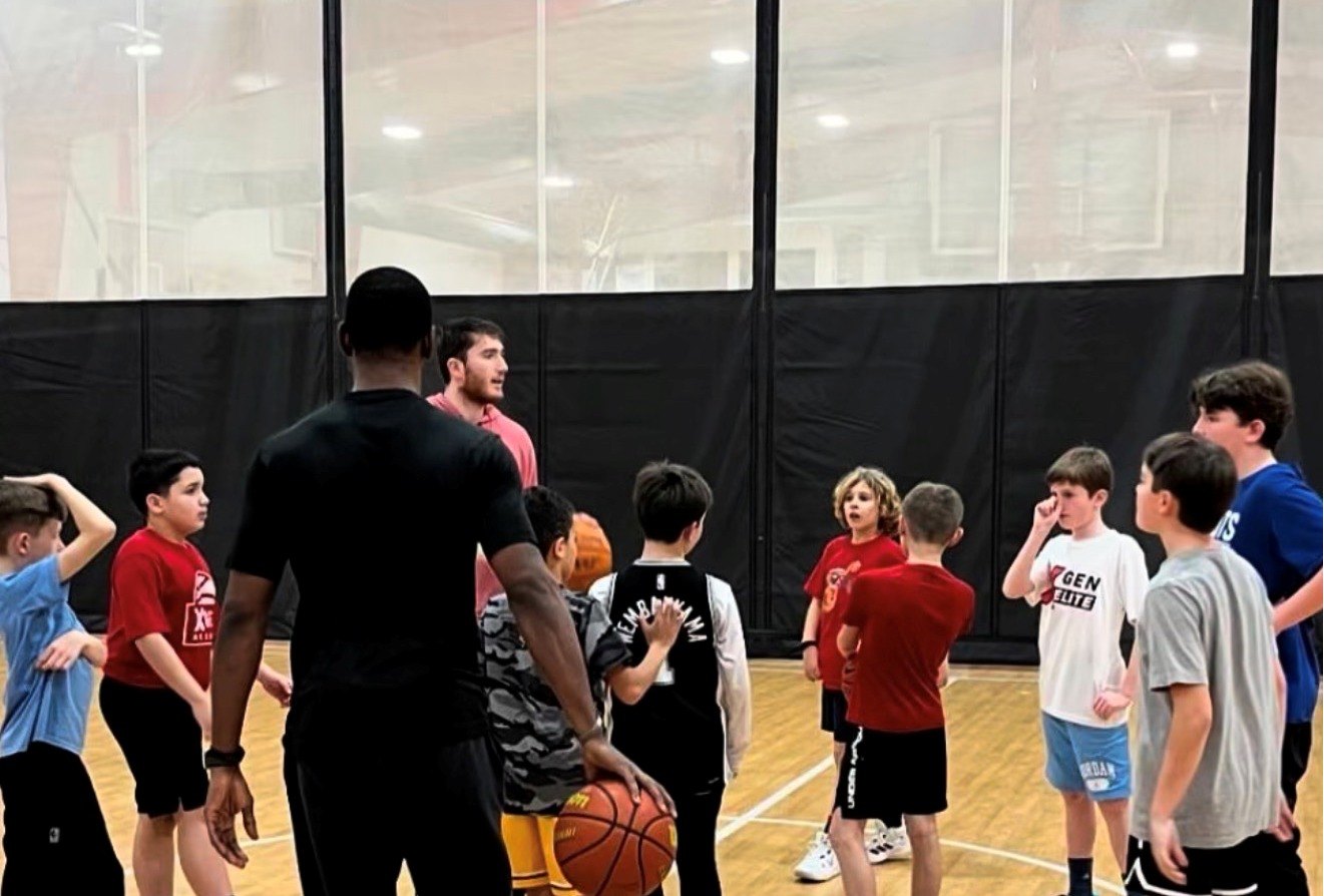 An XGEN coach addressing a circle of young players during an Academy training session